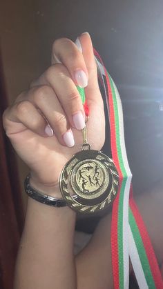 a woman holding up a medal with her hand on the other side of her arm