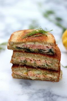 a sandwich cut in half sitting on top of a white marble counter next to lemons