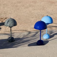 three blue and gray lamps sitting in the sand