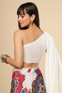 Introducing the Chiara Silk Shoulder Drape Blouse in White. On one side we have a spaghetti strap and on the other a free flowing drape. Oh what fun you can have with this piece, pair with with almost any bottom! An amalgamation of minimalism and elegance, this cropped top with an unconventional silhouette is true to One Minute Saree design values. Item Type: Saree blouse / Crop top Color: White Material: Silk Closure: Side Zip Neckline: Sweetheart Sleeves Type: One Shoulder Blouse Pattern: One Fitted Padded Blouse Camisole For Summer, White Blouse With Asymmetrical Neckline For Summer, White Sleeveless Blouse For Summer, Summer White Padded Blouse Piece, White Camisole Blouse For Party, Drapey Summer Party Top, White Asymmetrical Neckline Blouse For Summer, Fitted Sleeveless Blouse For The Beach, Fitted Blouse With Spaghetti Straps For Summer