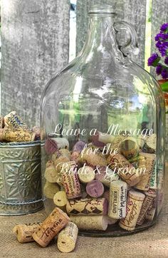 a glass bottle filled with wine corks next to a metal bucket full of flowers