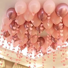 a room filled with lots of pink and brown heart shaped balloons hanging from the ceiling