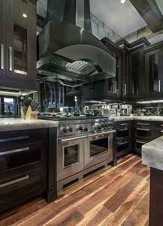 a large kitchen with black cabinets and stainless steel stove top oven in the center of the room