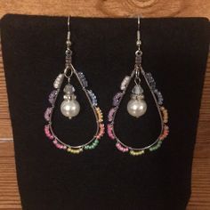 a pair of earrings with pearls and beads hanging from it's earwires