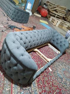 a gray couch sitting on top of a rug next to a pile of wood pallets