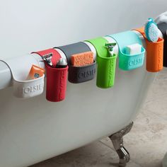 a bath tub filled with lots of different colored toothbrushes hanging from it's hooks