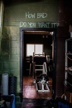 an open door leading into a room with graffiti on the wall and below it is a gym equipment rack