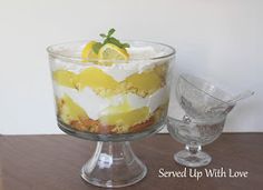 a dessert with lemons and whipped cream in a glass dish on a wooden table