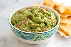 a bowl filled with guacamole next to chips