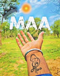 a man's hand with the word maa tattooed on it, in front of a green field