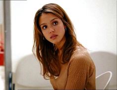 a woman sitting on a white chair looking at the camera