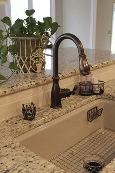 a sink in a kitchen next to a window with potted plants on the counter