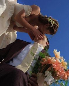 a bride and groom kissing in front of the sky with flowers on their lapel