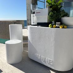 a white counter sitting on the side of a building next to a potted plant