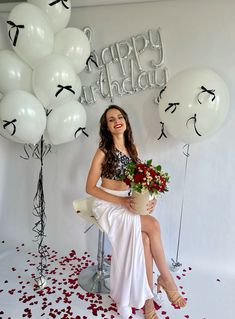 a woman sitting on a chair with flowers and balloons