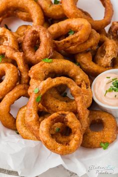 fried onion rings with dipping sauce on the side and garnished with parsley