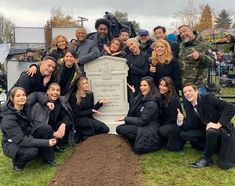 a group of people posing in front of a grave