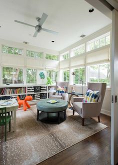 a living room filled with lots of furniture next to a window covered in bookshelves