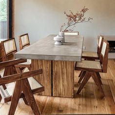 a dining room table with chairs around it and a vase on the end shelf above