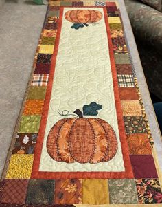 a quilted table runner with a pumpkin on it