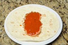 a tortilla with ketchup on it sitting on a plate