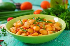 a green bowl filled with chickpeas on top of a table