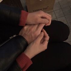 two hands holding each other while sitting on the floor in front of a pizza box