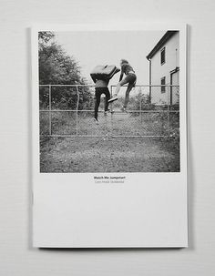 an old photo of two people playing tennis on a fenced in area with trees