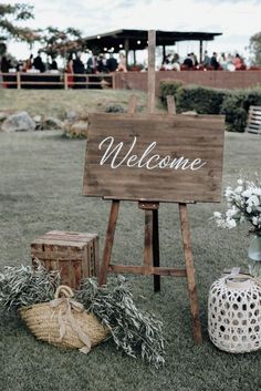 a wooden welcome sign sitting on top of a lush green field next to other decorations