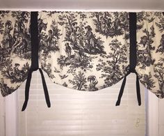 a window curtain with black and white fabric hanging from it's side, in front of a window