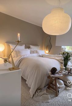 a white bed sitting in a bedroom next to two lamps and a table with flowers on it