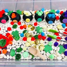 a plastic container filled with lots of different colored candies and buttons next to a wooden spoon