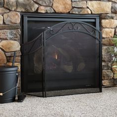 a fireplace with a fire in it next to a potted plant and a bucket