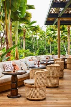 an outdoor seating area with wicker furniture and palm trees in the background on a wooden deck