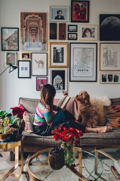 a woman sitting on top of a couch next to a dog in a living room