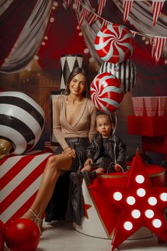 a woman sitting next to a child in front of christmas decorations