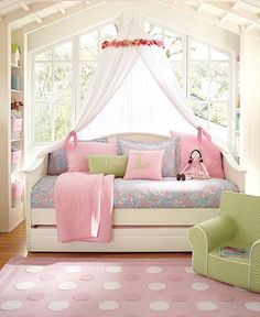 a day bed with pink and green pillows in a girls's bedroom, next to a window