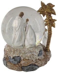 a snow globe with two figurines in it and a palm tree on top