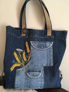 a denim bag with embroidered flowers on the front and side pocket, sitting on a table