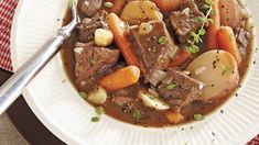 a white plate topped with meat and veggies covered in gravy next to a fork