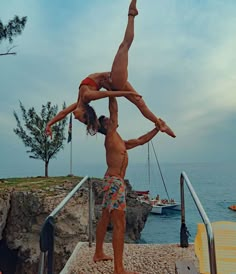 two people are doing acrobatic tricks on the steps by the water's edge