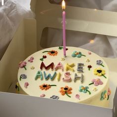 a birthday cake with the word amsw on it and a single lit candle sticking out of it