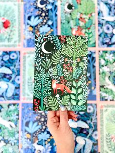 a person holding up a card with an image of animals and plants on it in front of colorful tiles