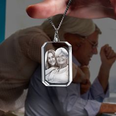 an elderly woman holding her granddaughter in front of the camera, while she is wearing a silver necklace