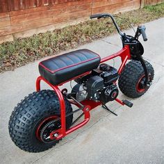 a small red motorcycle sitting on top of a sidewalk