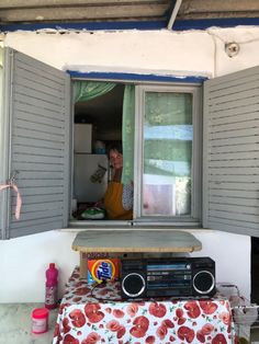 a man is looking out the window with his radio in front of him and food on the table behind him