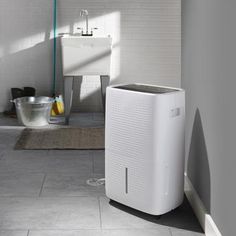 a white air purifier sitting on top of a tiled floor next to a sink