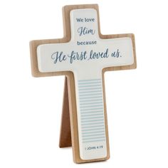 a wooden cross with the words, we love him because he first loved us