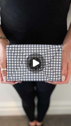 a woman is holding a box with a black and white checkered design on it