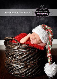 a newborn baby wearing a santa hat in a basket